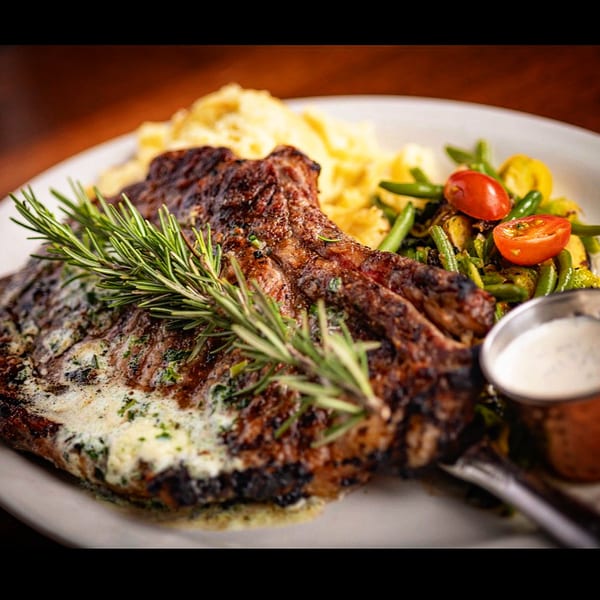 Juicy grilled steak with rosemary, mashed potatoes, roasted vegetables, and creamy sauce.