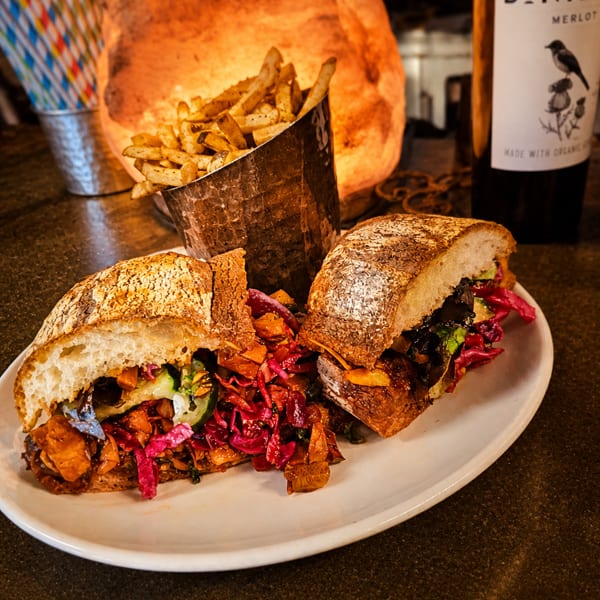 Hearty sandwich with red cabbage and fries, next to a Bonterra Merlot bottle.