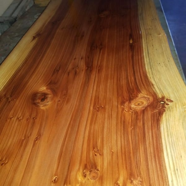 Polished live-edge wooden surface showcasing natural grain patterns and knots.