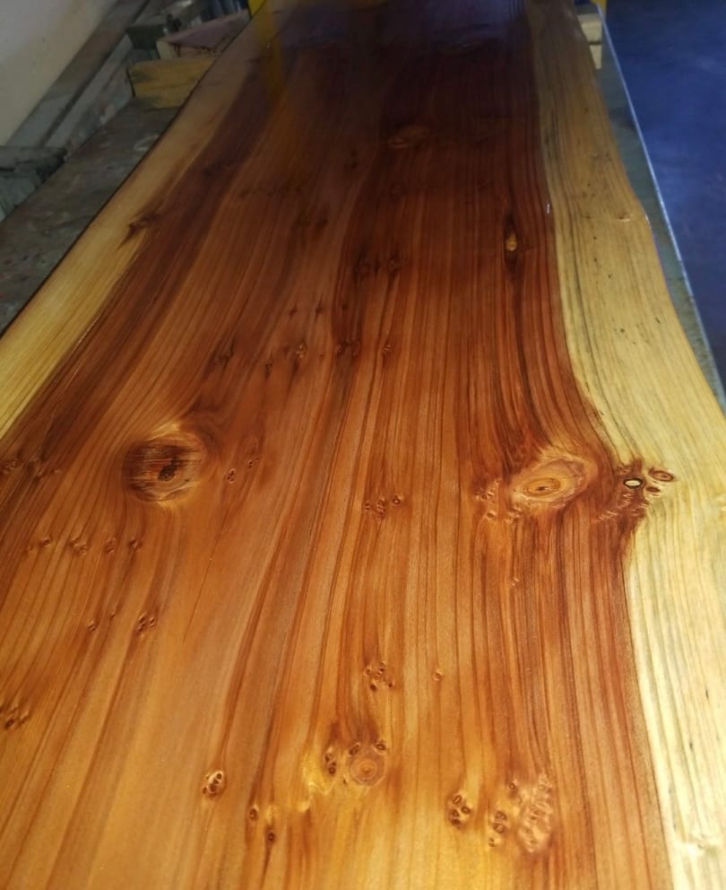 Polished live-edge wooden surface showcasing natural grain patterns and knots.